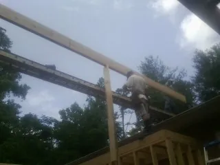 Carpenter setting a ridge beam over a new addition frame — Ice Dam Removal by Roofing Brothers in Wellpinit