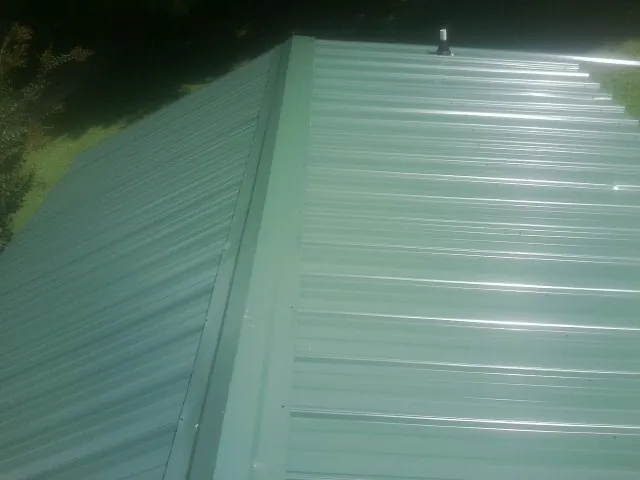 New green metal panels meeting at the ridge of a roof — Flat Roof Repair work by our crew in Wellpinit