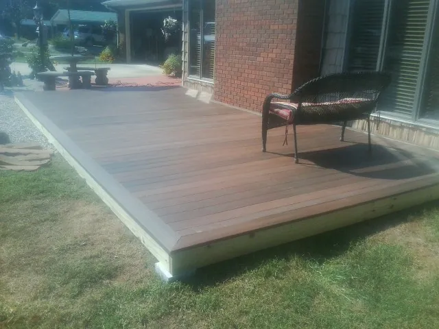 New wood deck and wicker chair beside a brick house in Wellpinit