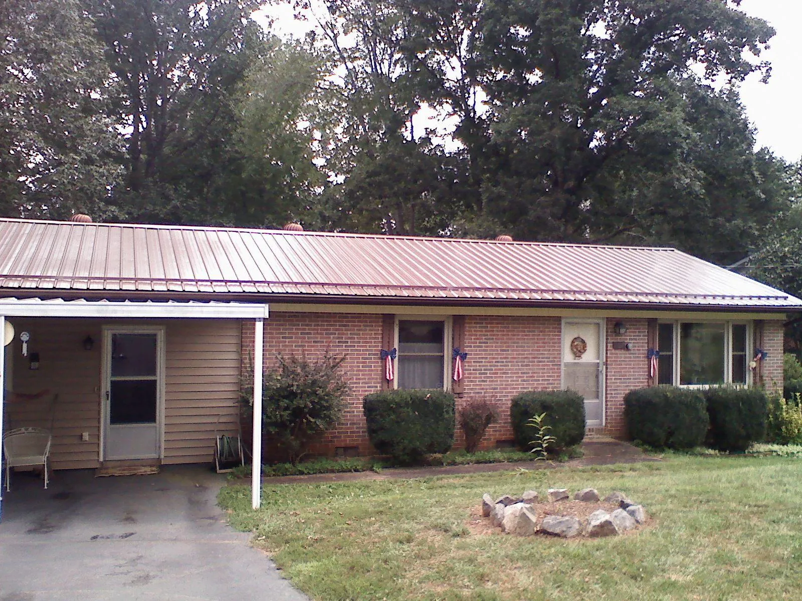Bronze metal roof and carport on a brick ranch home — Roof Repair work by our crew in Wellpinit