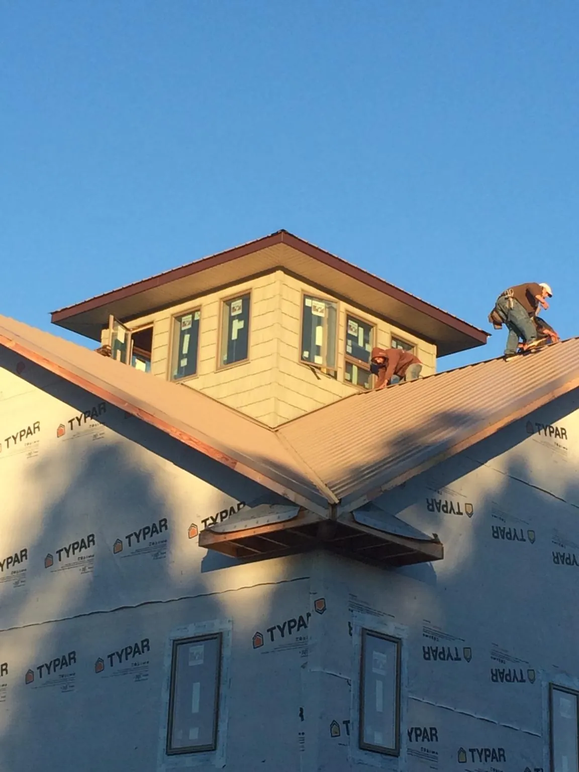 Roofers working around a rooftop cupola on a new metal roof at sunset — Roof Waterproofing in Wellpinit by Roofing Brothers